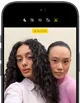 iPhone 18 Pro, noir, face avant, affichant deux modèles qui posent pour la caméra, mettant en avant la caméra avant Center Stage